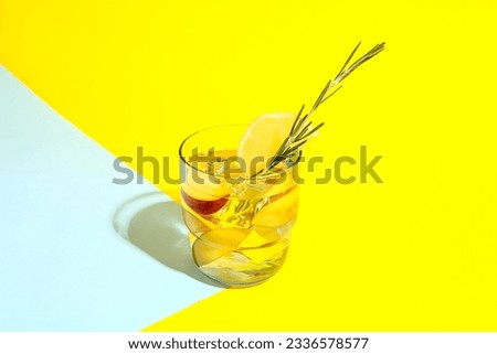 Glass of fresh peach lemonade with rosemary on colorful background