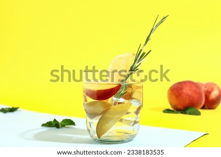 Glass of fresh peach lemonade with rosemary and mint on colorful background