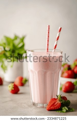 Glass of fresh strawberry milkshake, smoothie and fresh strawberries on light background. Healthy food and drink concept.