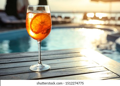 Glass of fresh summer cocktail on wooden table near swimming pool outdoors at sunset. Space for text - Powered by Shutterstock