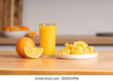 Glass Of Freshly Squeezed Orange Juice On Wooden Tabletop, Orange Pulp In Plate, Close-up Of Orange Slice.