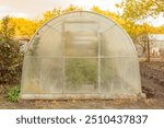 Glass garden greenhouse in autumn. Fall foliage in the garden. Greenhouse stretches the growing season, you can start growing earlier every year and enjoy your vegetables during the fall months.