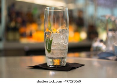 A glass of gin on a bar with a blurred background