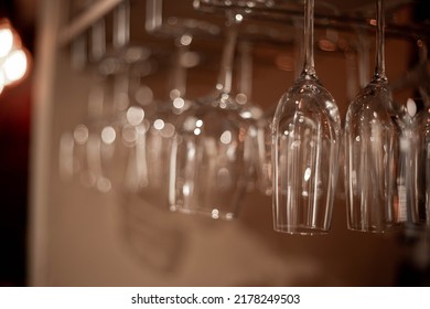 Glass Glasses For Cognac Are Suspended Above The Bar Counter On A Brown Background