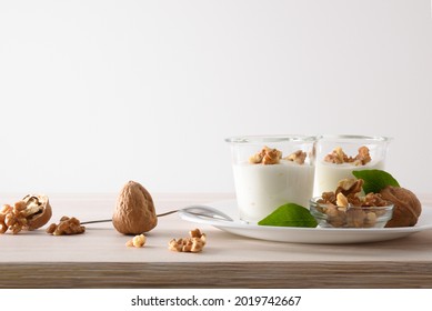 Glass Glasses With Yogurt With Walnuts And Bowl With Walnuts On Wooden Table Isolated Background. Front View.