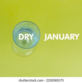 a glass goblet with water on a green background with copy space and the inscription Dry January. - Powered by Shutterstock