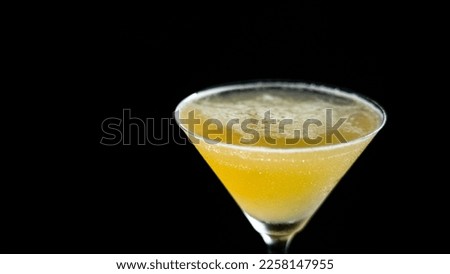 A glass of golden cocktail on a black background