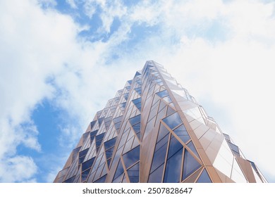 glass golden copper blue futuristic modern skyscraper building facade, wall on cloudy sky. view from below - Powered by Shutterstock