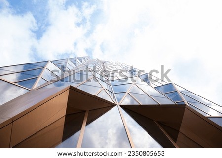 glass golden futuristic modern skyscraper building facade, wall on cloudy sky. view from below