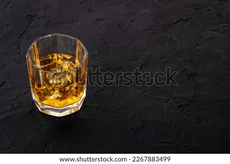 Glass of golden whiskey with ice. Strong alcoholic drink background.