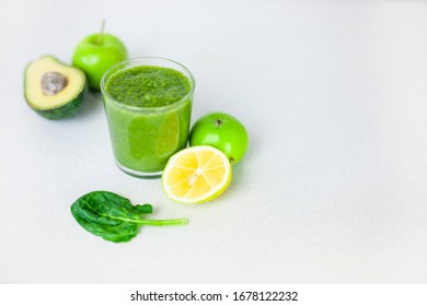 Glass Of Green Smoothie Detox Drink And A Set Of Products For Preparation: Lemon, Apple, Avocado, Spinach. Morning Detox For A Healthy Lifestyle, Weight Loss, Ketone Diet, Raw Food Diet