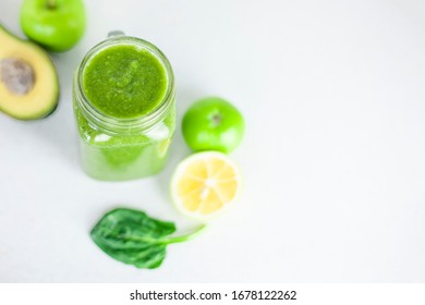 Glass Of Green Smoothie Detox Drink And A Set Of Products For Preparation: Lemon, Apple, Avocado, Spinach. Morning Detox For A Healthy Lifestyle, Weight Loss, Ketone Diet, Raw Food Diet