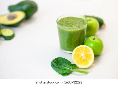 Glass Of Green Smoothie Detox Drink And A Set Of Products For Preparation: Lemon, Apple, Avocado, Spinach. Morning Detox For A Healthy Lifestyle, Weight Loss, Ketone Diet, Raw Food Diet