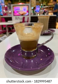 Glass Of Half Empty Coffee Piccolo Latte On A Purple Saucer 