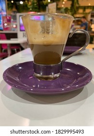 Glass Of Half Empty Coffee Piccolo Latte On A Purple Saucer 