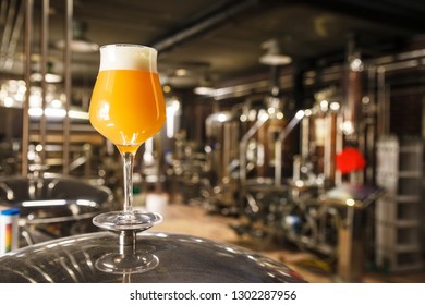 A Glass Of Hazy IPA Beer Standing On A Tank In A Functional Brewery