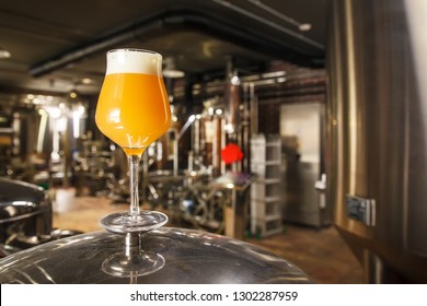 A Glass Of Hazy IPA Beer Standing On A Tank In A Functional Brewery