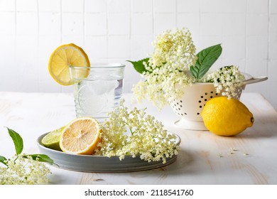 Glass of homemade elderflower lemonade with lemon, lime juice and freshly picked elderberry flowers. Healthy refreshing  mocktail with elderflower cordial syrup