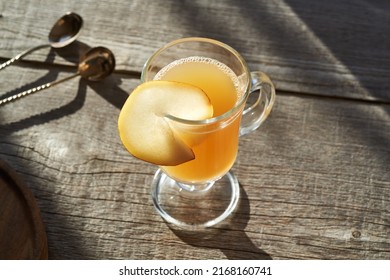 A Glass Of Hot Pear Drink On A Wooden Table In Sunlight