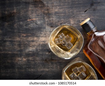 Glass With Ice Cubes And Whiskey Bottle On Wooden Table,top View