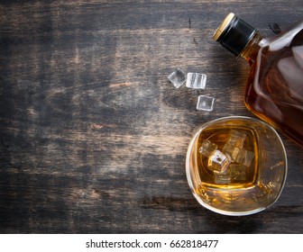 Glass With Ice Cubes And Whiskey Bottle On Wooden Table,top View