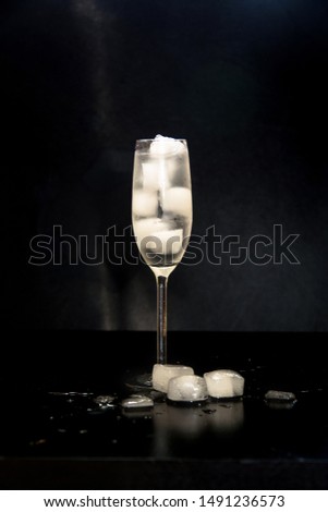 glass with ice on a black background. melting ice around splashing drops