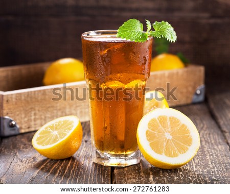 glass of ice tea with mint and lemon on wooden table