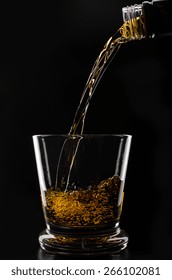 Glass With Ice In Which Pour Whiskey On A Black Background