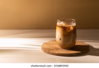 Glass of a iced coffee with cream milk. Cold brew coffee drink with ice. Early morning sun light. Copy space.