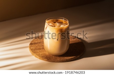Glass of a iced coffee with cream milk. Cold brew coffee drink with ice. Early morning sun light. 