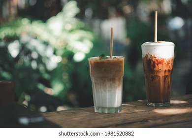 Glass Of Iced Latte Coffee And Iced Mocha Placed On Wood Table With Garden Background At Outdoor Cafe