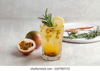 A glass of Iced passion fruit soda with lemon and passion fruit half slice on grey background, a healthy summer drink - Shutterstock ID 2107987172