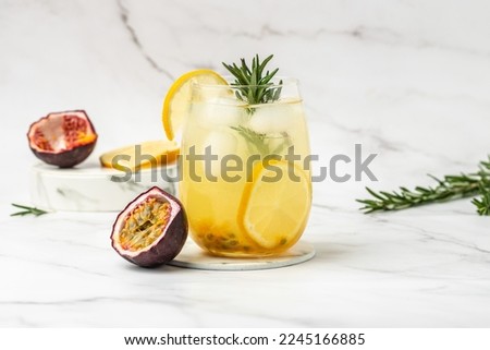 glass of Iced passion fruit soda with lemon and passion fruit half slice on a light background, refreshing drink or beverage with ice, place for text,
