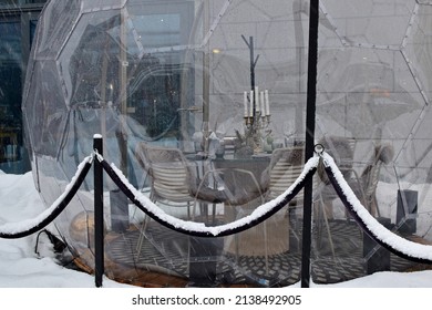 Glass Igloo Terrace In Front Of Restaurant Gustav  In Winter During Snowstorm. Silhouette Of Catered Table Inside The Igloo