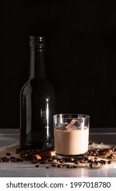 A Glass Of Irish Cream Coffee Liqueur With Ice And Ice. Coffee Beans, Black Bottle.