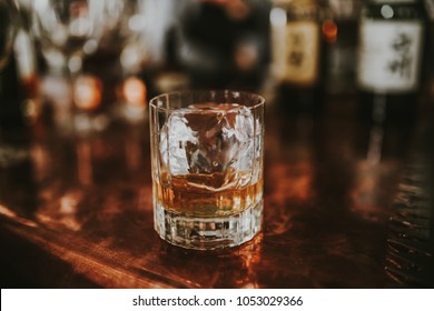 A Glass Of Japanese Whisky With A Cube Of Ice On The Bar Station