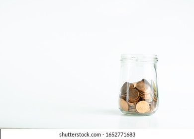 a glass jar of bronze coins on isolated white background.