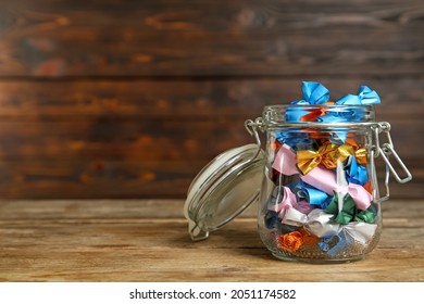 Glass jar with candies in colorful wrappers on wooden table. Space for text - Powered by Shutterstock