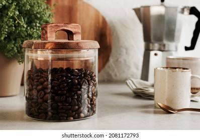 Glass jar with coffee beans, wooden kitchenware. Modern kitchen backdrop. Breackfast lifestyle. Toned.  - Powered by Shutterstock