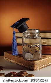 Glass jar with coins and graduation hat on books, scholarship concept. Vertical image