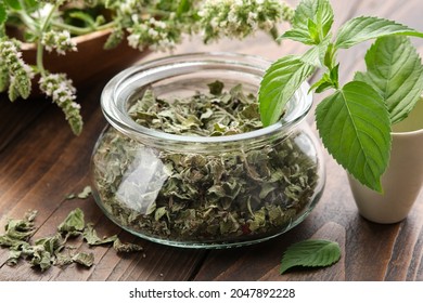 Glass jar of dried mint leaves and blossom peppermint. Mortar of fresh spearmint leaves. Wooden bowl of blossom Mentha piperita medicinal plants on background. - Powered by Shutterstock