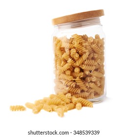 Glass jar filled with dry rotini yellow pasta over isolated white background