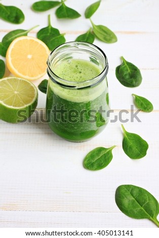 Glass jar of fresh summery drink green smoothie, spinach leaves, lime fruit. Vertical.