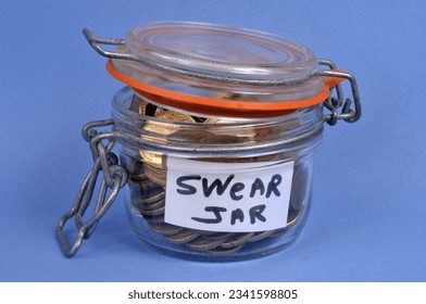 Glass jar full of coins for swearing close up on blue background 