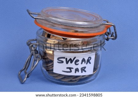 Glass jar full of coins for swearing close up on blue background 