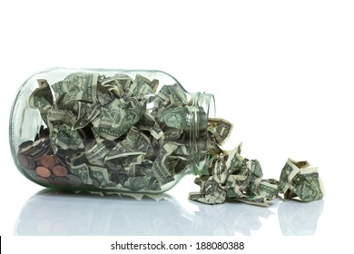 Glass Jar Full Of Money Tipped Over On Its Side Spilling Money