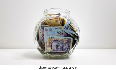 Glass Jar Full Of Romanian RON Bank Notes On A White Background