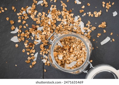 Glass jar of homemade organic granola with coconut and pecans on black background. Delicious breakfast cereal. Healthy muesli. - Powered by Shutterstock