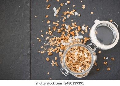 Glass jar of homemade organic granola with coconut and pecans on black background. Delicious breakfast cereal. Healthy muesli. - Powered by Shutterstock