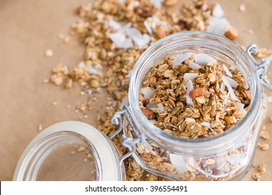 Glass jar of homemade organic granola with coconut and pecans on the baking paper background. Delicious breakfast cereal. Healthy muesli. - Powered by Shutterstock